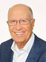 Elderly man smiling in a professional portrait.